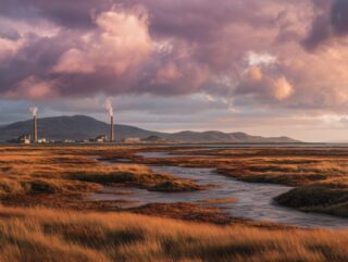 Golden-hour view of Islay’s rugged coast and peat bogs, smoke rising gently from a seaside distillery.