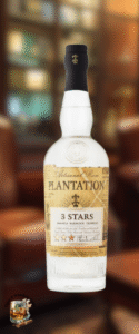 A clear glass bottle of Plantation 3 Stars rum with a cream and gold label, perfect for a mild cigars rum pairing. The black-capped bottle sits before a blurred, warm-toned library or lounge with bookshelves and cozy armchairs.