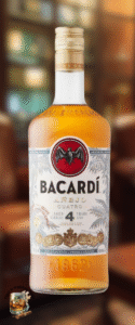A bottle of Bacard&iacute; A&ntilde;ejo Cuatro rum with a gold cap, red bat logo, and label stating it is aged 4 years. The softly blurred bar background hints at a cozy lounge, ideal for a mild cigars rum pairing. &ldquo;Code of Whiskey&rdquo; logo sits bottom left.